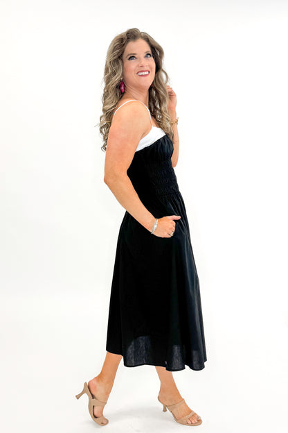 Side view of woman wearing Black With White Color Block Smocked Midi Dress against white studio background.