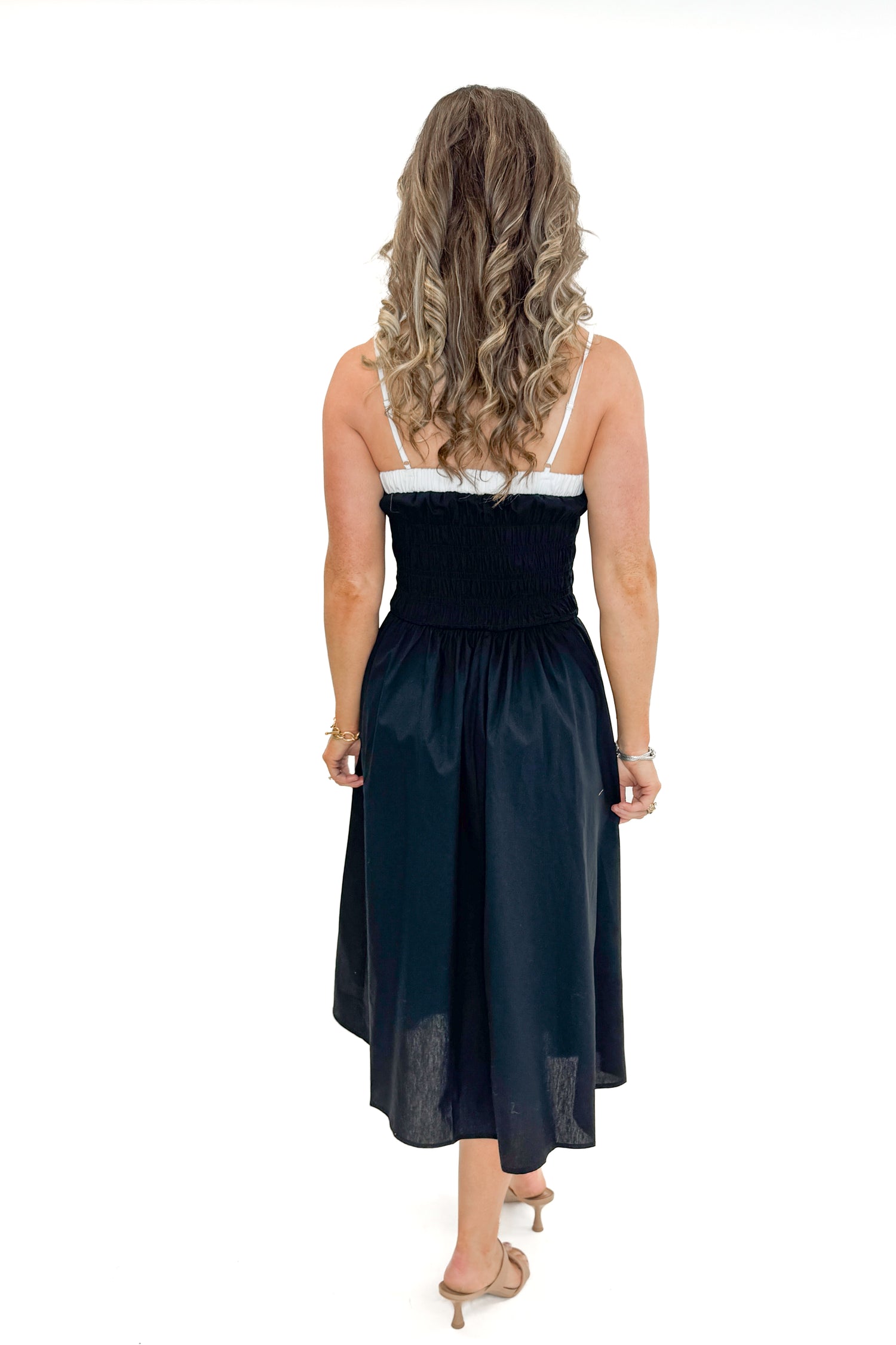 Back view of woman wearing Black With White Color Block Smocked Midi Dress against white studio background.