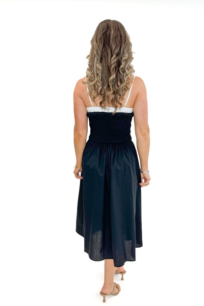 Back view of woman wearing Black With White Color Block Smocked Midi Dress against white studio background.