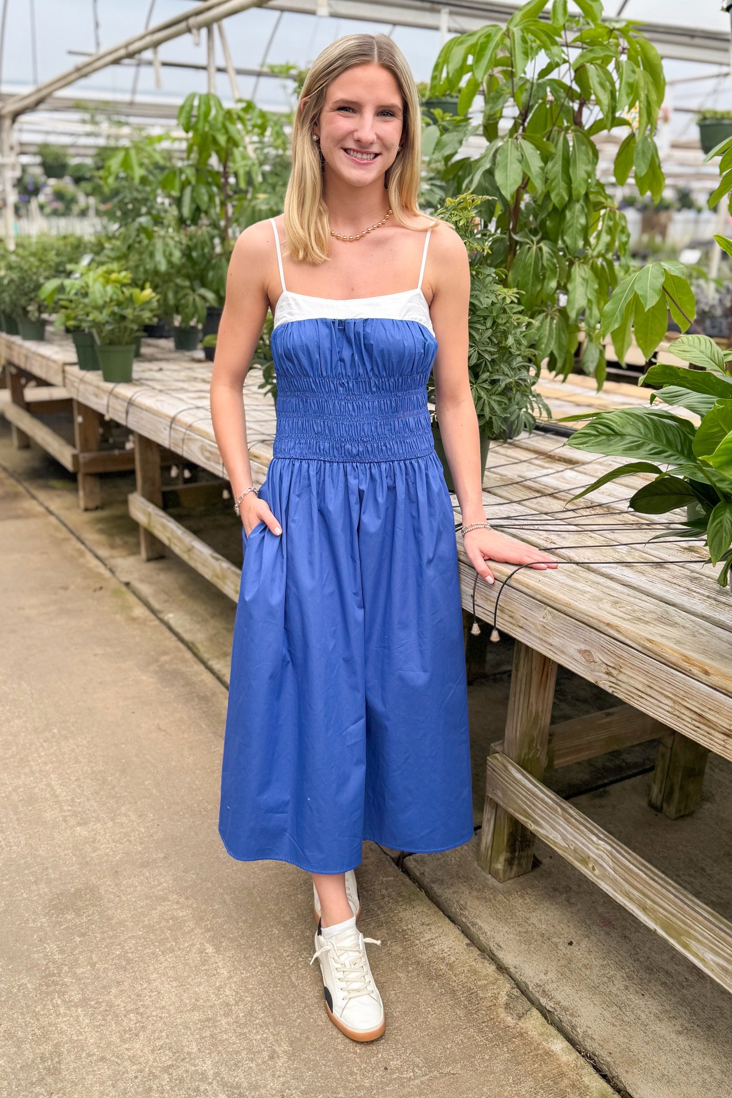 Front view of woman wearing Blue With White Color Block Smocked Midi Dress at a garden center.