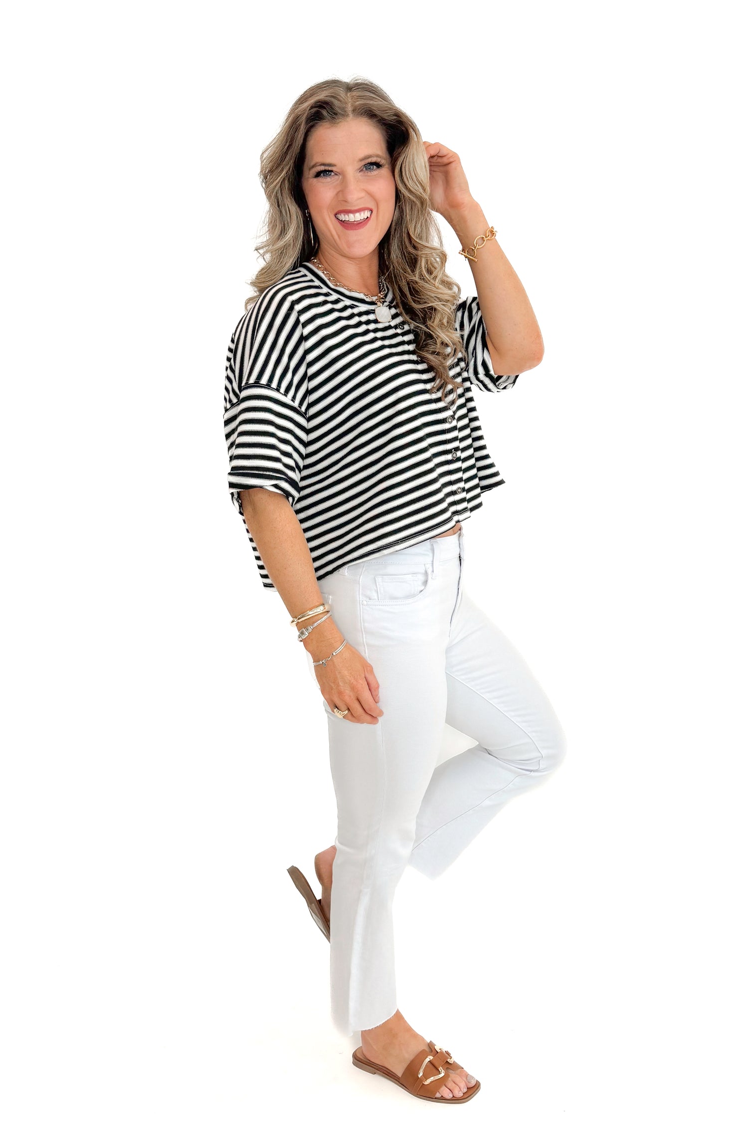 Side view of woman wearing Black &amp; White Striped Button Up Tee with jeans against white studio background.