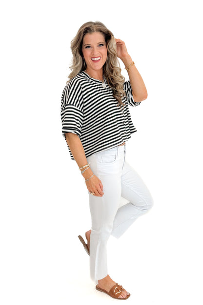 Side view of woman wearing Black &amp; White Striped Button Up Tee with jeans against white studio background.