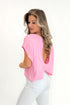 Side view of woman wearing Pink Cut Out Back Tee with jeans against white studio background.