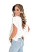 Side view of woman wearing White Cut Out Back Tee with jeans against white studio background.