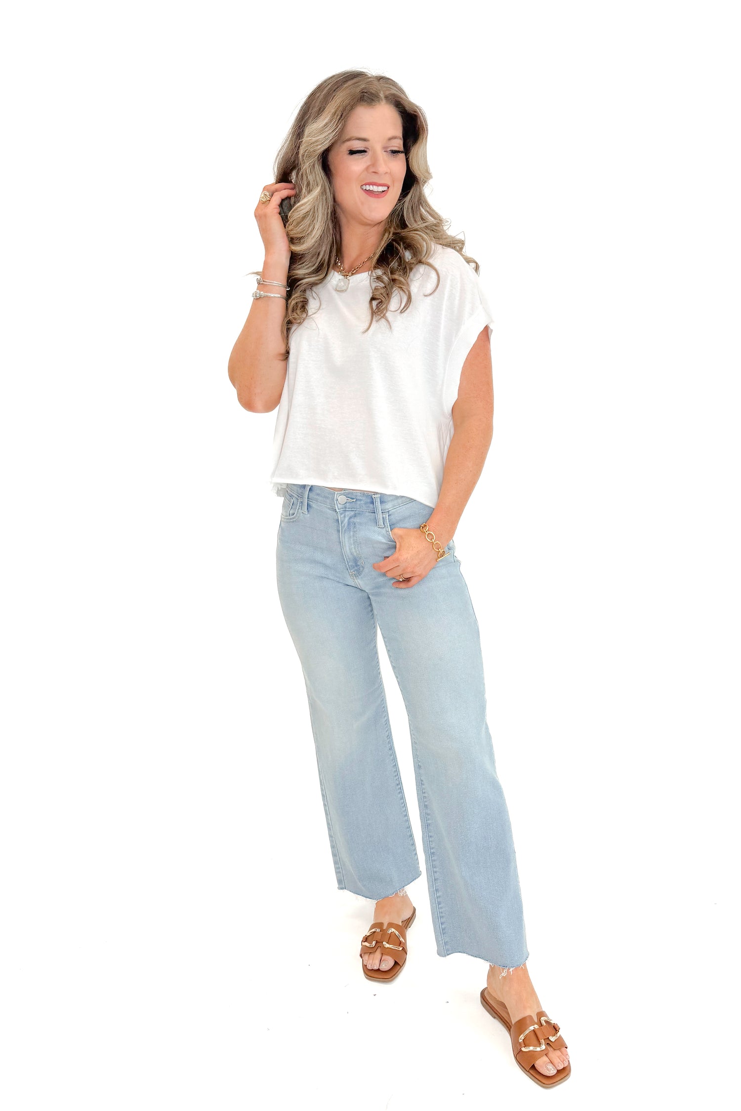Front view of woman wearing White Cut Out Back Tee with jeans against white studio background.