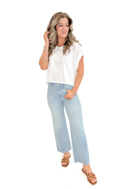 Front view of woman wearing White Cut Out Back Tee with jeans against white studio background.