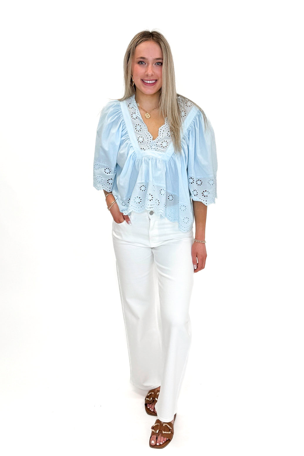 Front view of woman wearing Light Blue Eyelet Babydoll Top with jeans against white studio background.