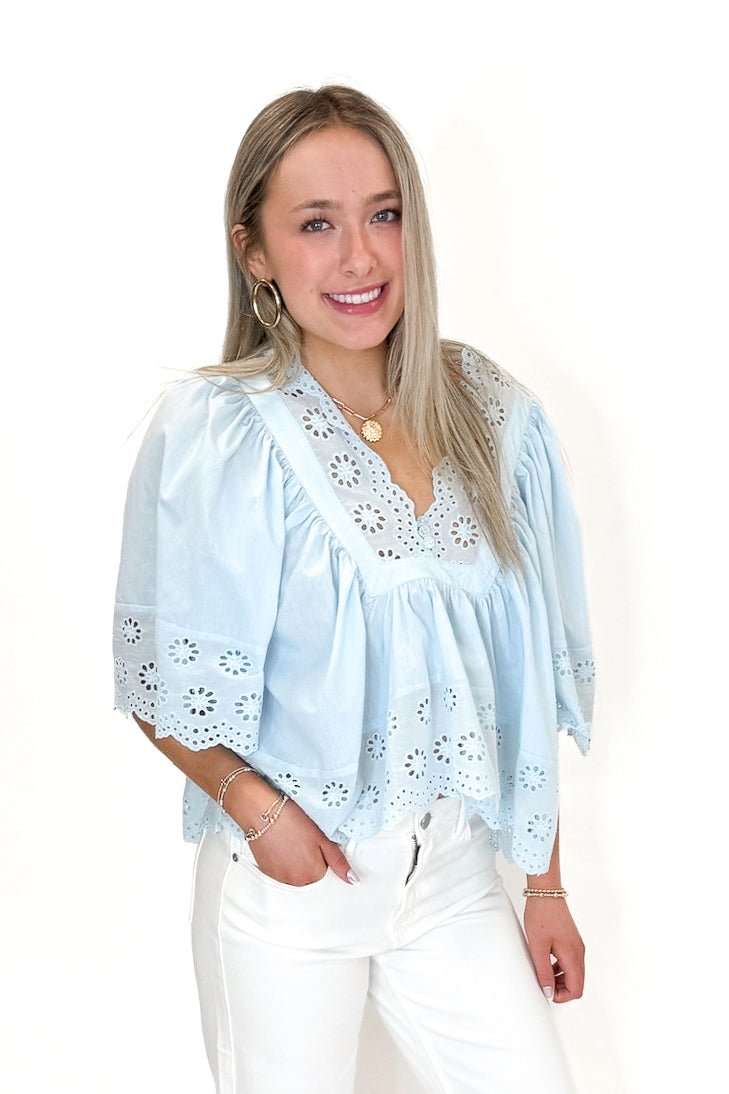 Front view of woman wearing Light Blue Eyelet Babydoll Top with jeans against white studio background.