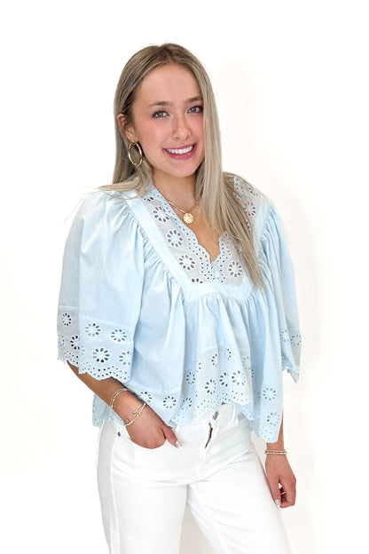 Front view of woman wearing Light Blue Eyelet Babydoll Top with jeans against white studio background.
