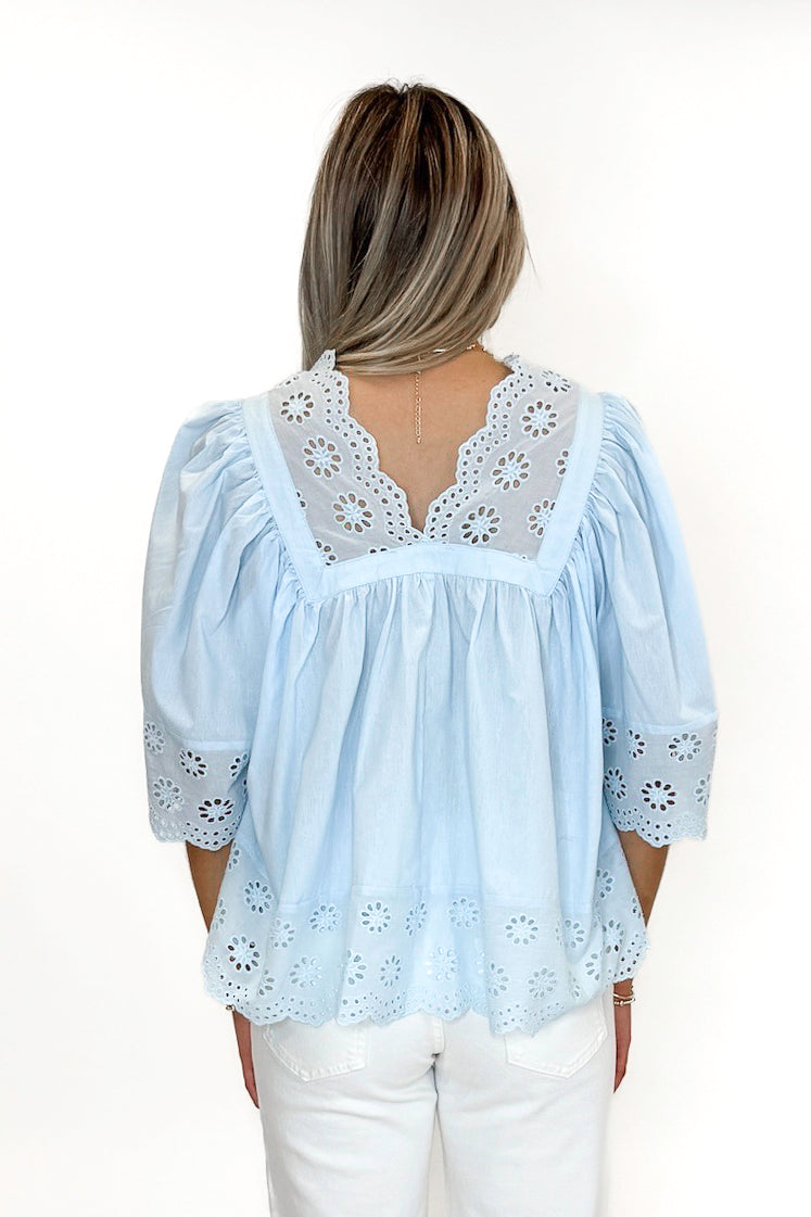 Back view of woman wearing Light Blue Eyelet Babydoll Top with jeans against white studio background.