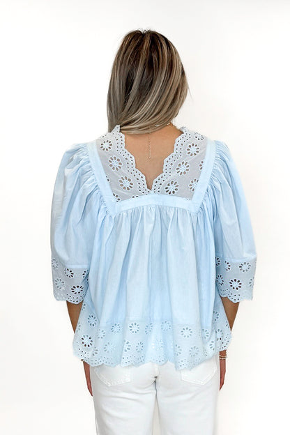 Back view of woman wearing Light Blue Eyelet Babydoll Top with jeans against white studio background.