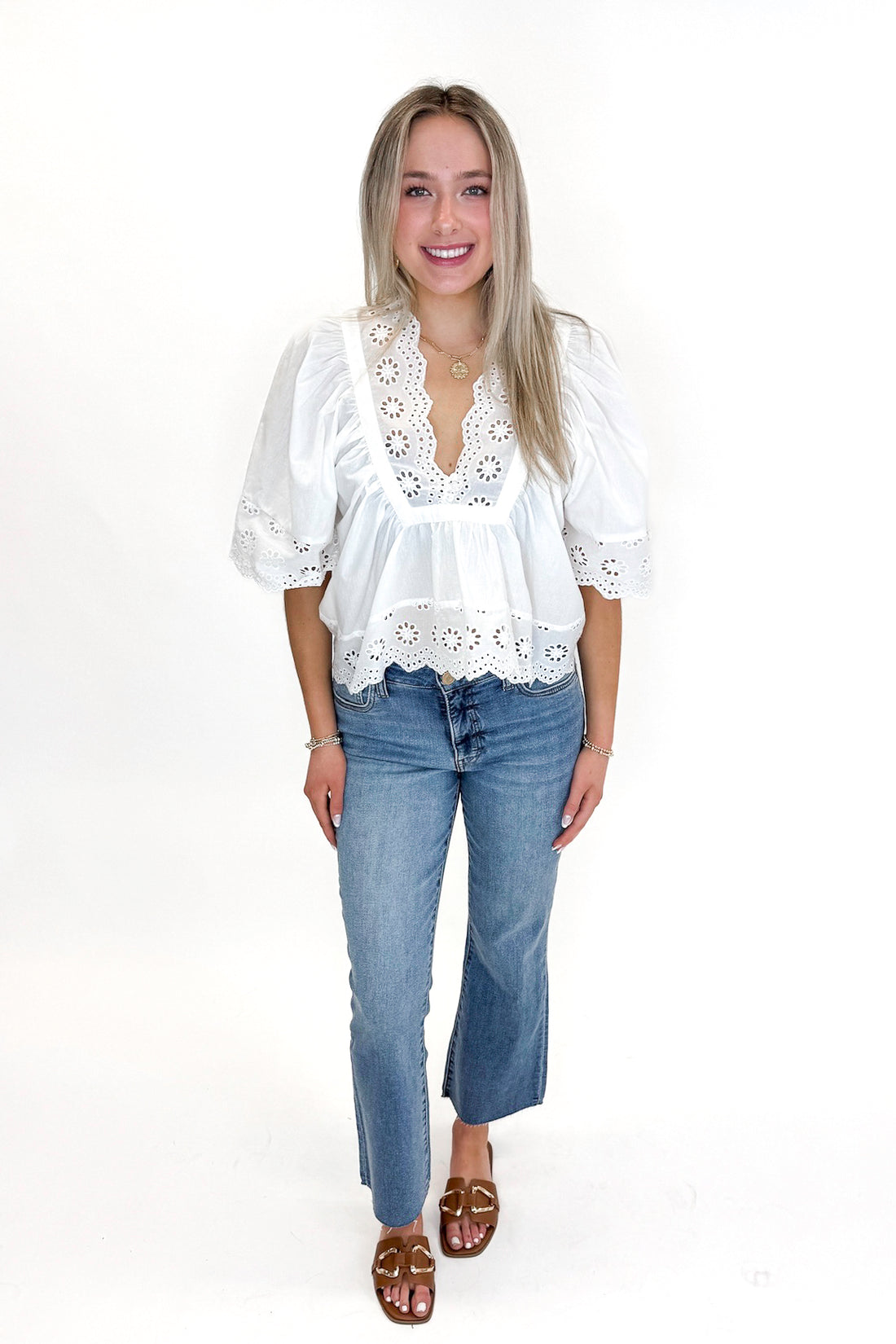 Front view of woman wearing White Eyelet Babydoll Top with jeans against white studio background.