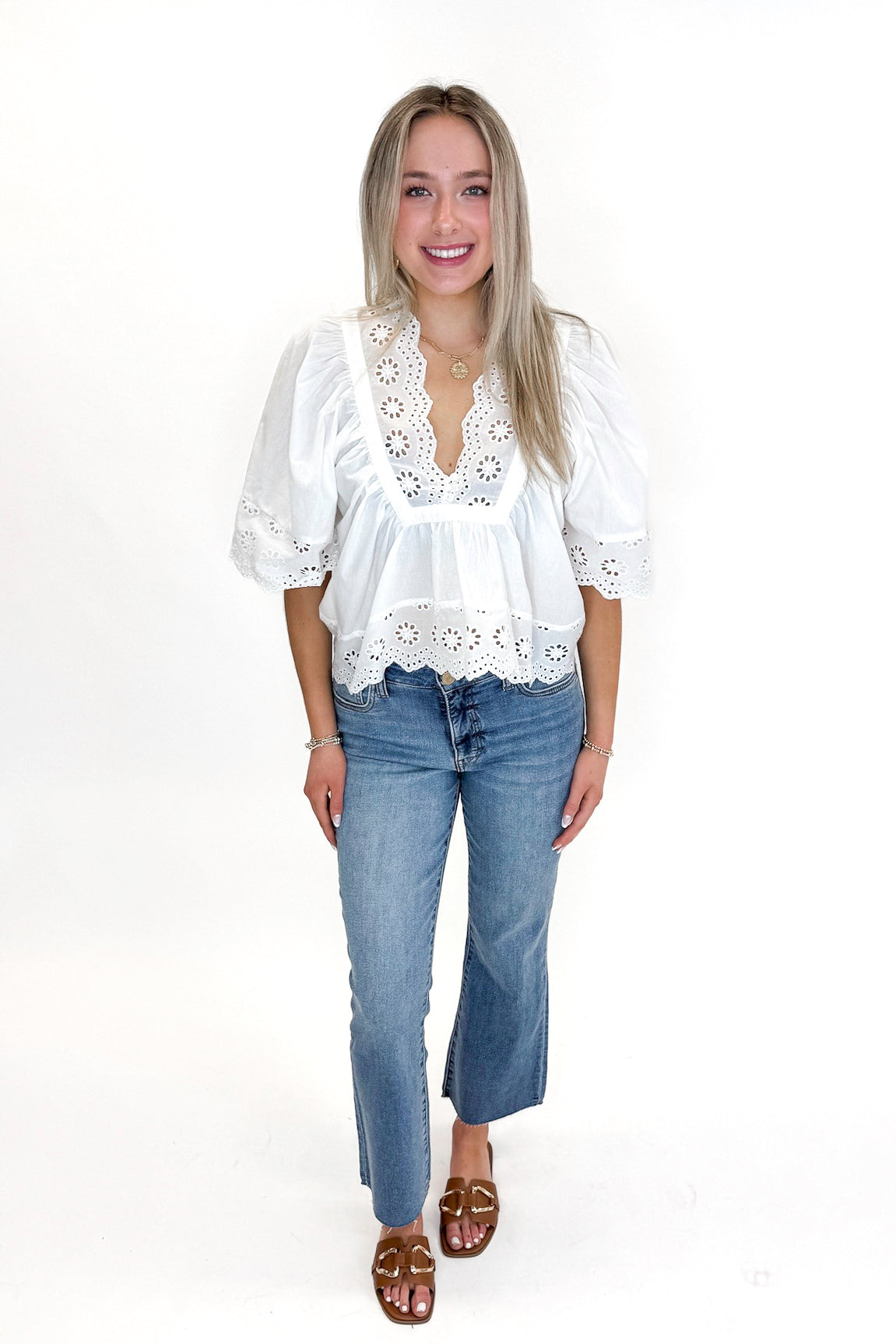 Front view of woman wearing White Eyelet Babydoll Top with jeans against white studio background.