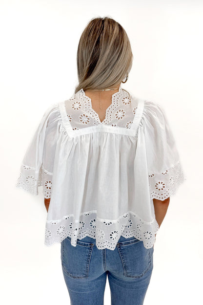 Back view of woman wearing White Eyelet Babydoll Top with jeans against white studio background.