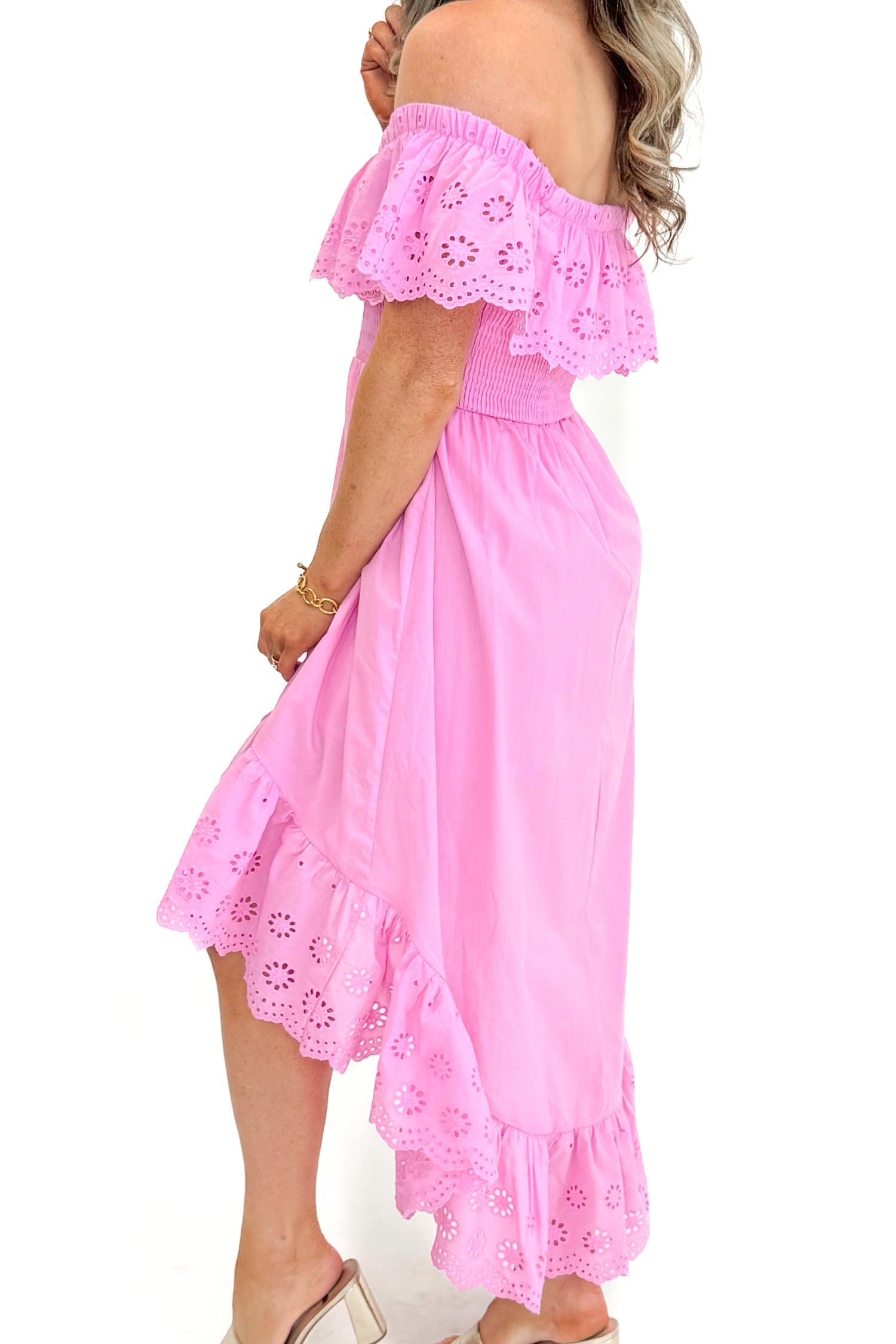 Side detail view of woman wearing Pink Eyelet Detail Hi-Low Dress against white studio background.