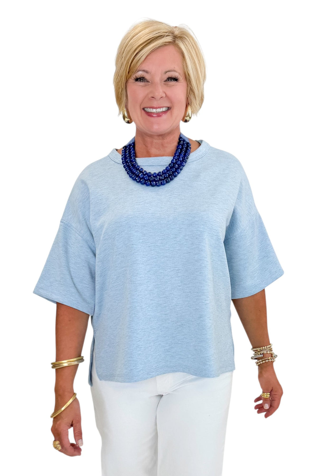 Front view of woman wearing Swagger Boutique’s Heathered Blue Short Sleeve Top with jeans against white studio background.