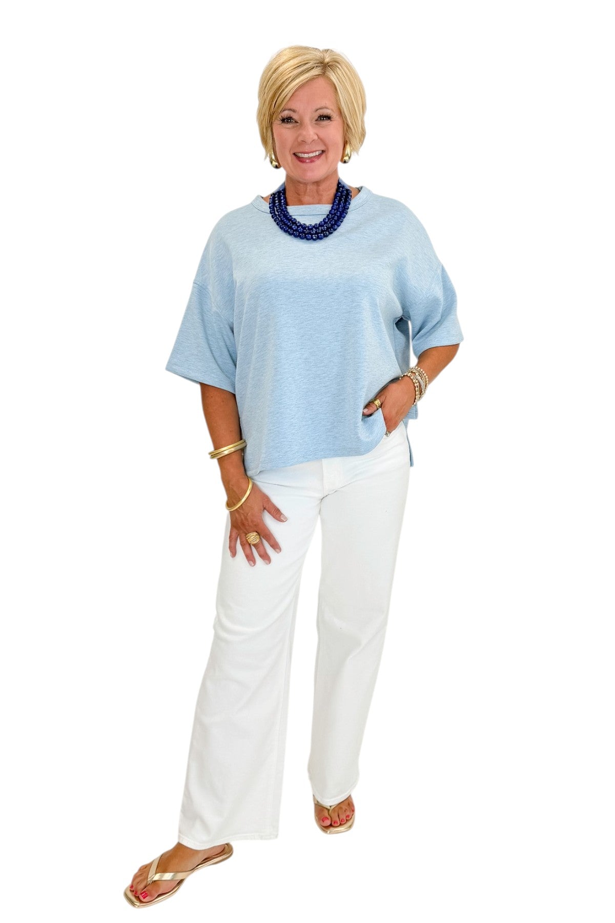 Front view of woman wearing Swagger Boutique’s Heathered Blue Short Sleeve Top with jeans against white studio background.