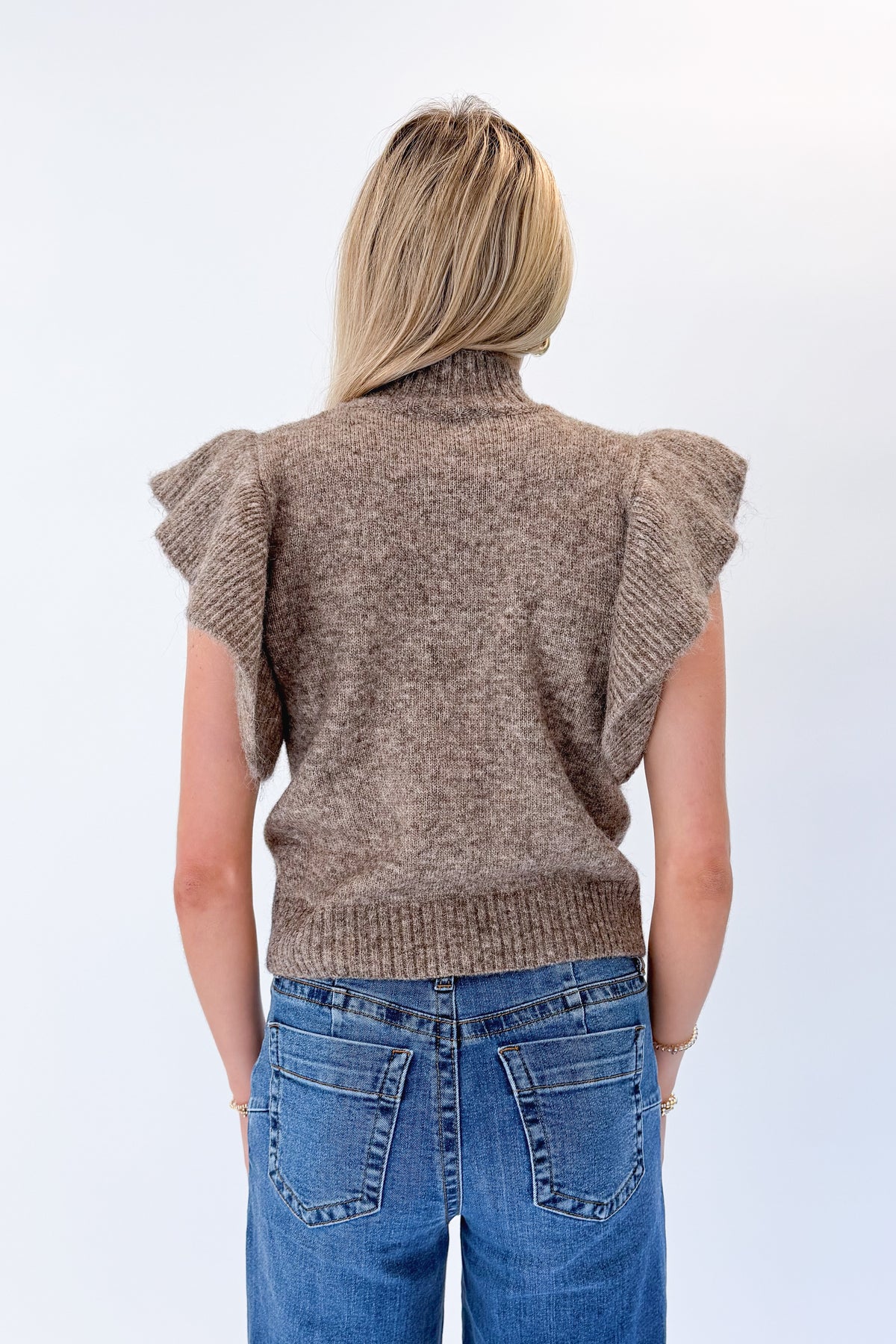 Back view of woman wearing Swagger Boutique’s Heathered Taupe Short Flutter Sleeve Sweater by Entro with jeans against white studio background.