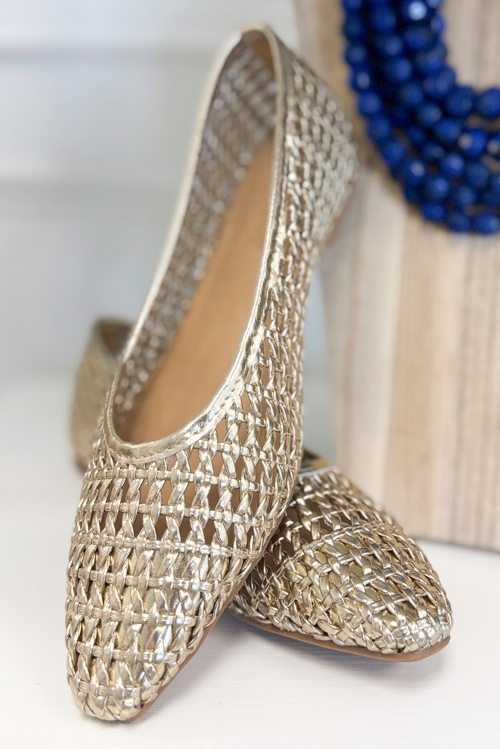 Swagger Boutique’s sweater Highway- Gold Woven Flats against white studio background.