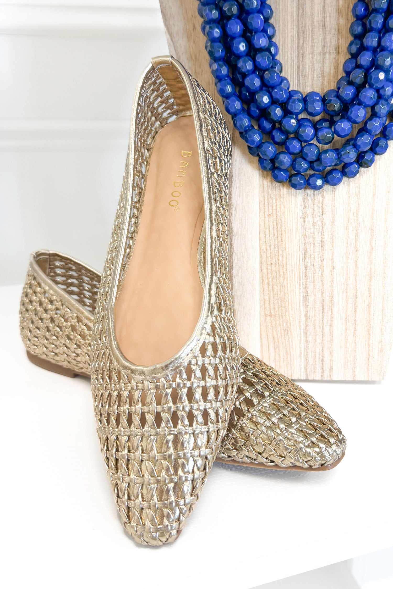 Swagger Boutique’s sweater Highway- Gold Woven Flats against white studio background.