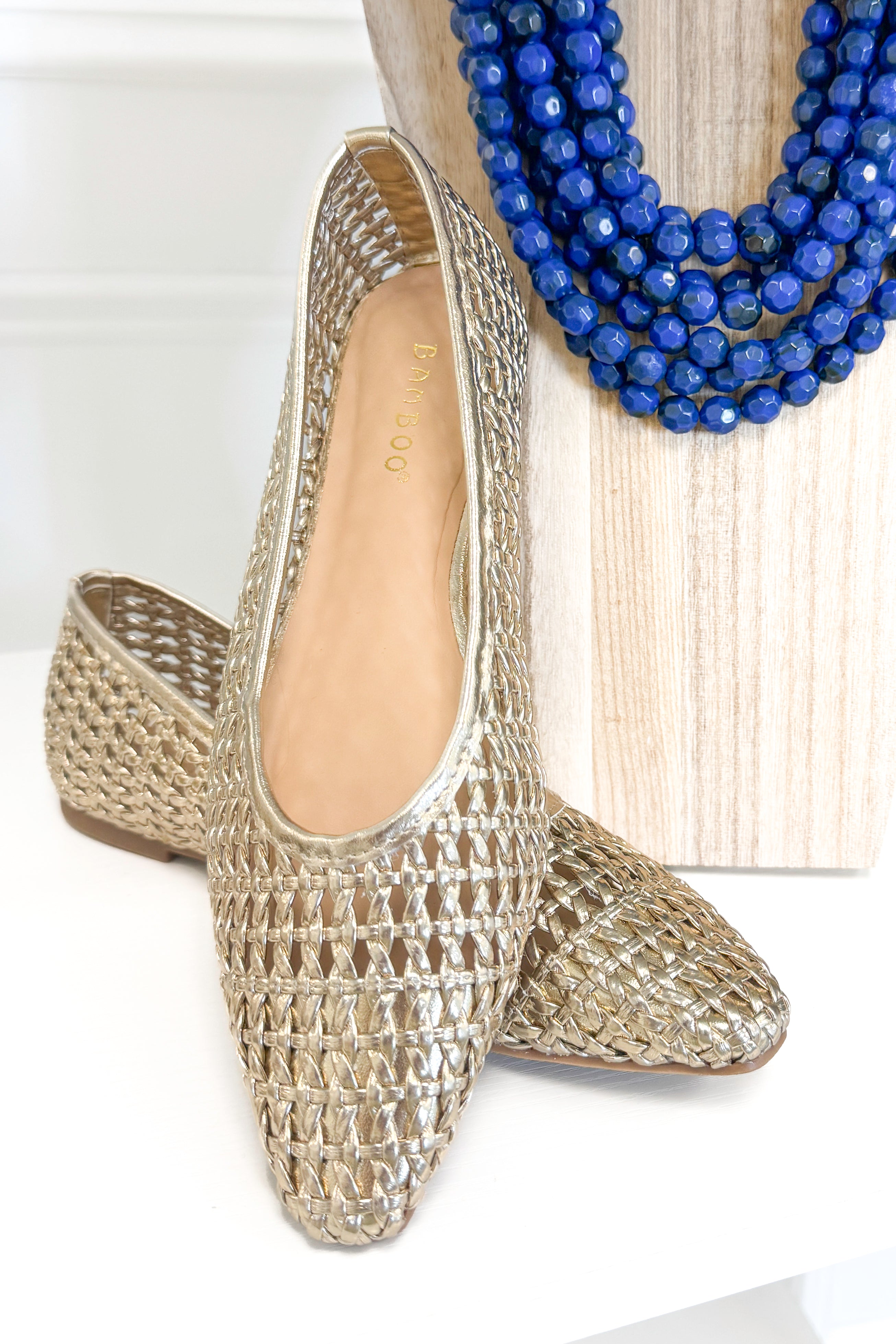 Swagger Boutique’s sweater Highway- Gold Woven Flats against white studio background.