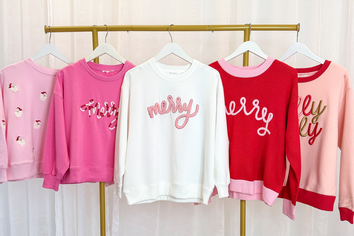 Holiday Sweatshirts hanging on a rack against a white background.