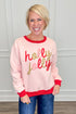 A smiling blonde woman wearing a light pink crewneck sweatshirt with red ribbed trim and &