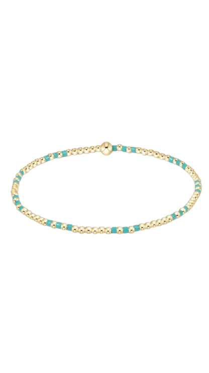 A delicate gold chain bracelet with small turquoise blue bead accents, displayed on a clean white background.