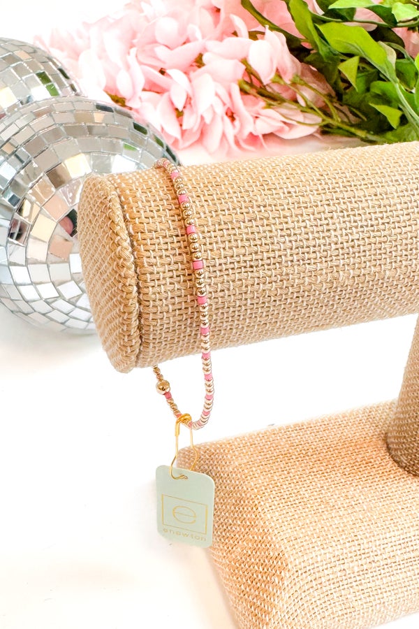 Pink beaded bracelet on a burlap roll with flowers and disco ball in the background
