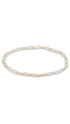 A delicate beaded bracelet featuring white pearls and small polished gold beads, arranged in a horizontal oval on a solid white background.