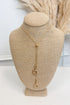 Gold-tone bolo necklace featuring a fine, reflective chain held together by a smooth, polished gold sphere slider, with delicate chain strands dropping vertically down the center each with a small horseshoe pendant 