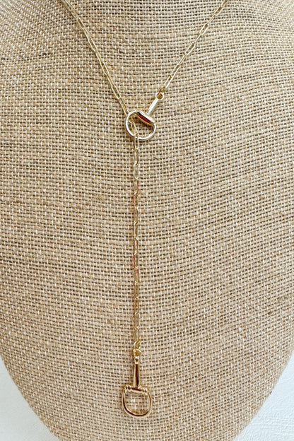Gold-tone delicate chain necklace featuring a small horsebit pendant, displayed on a beige jewelry bust