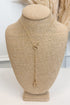 Gold-tone delicate chain necklace featuring a small horsebit pendant, displayed on a beige jewelry bust against a white studio background