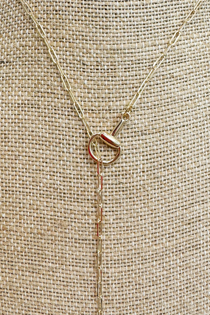 Close up of gold-tone delicate chain necklace featuring a small horsebit pendant, displayed on a beige jewelry bust 