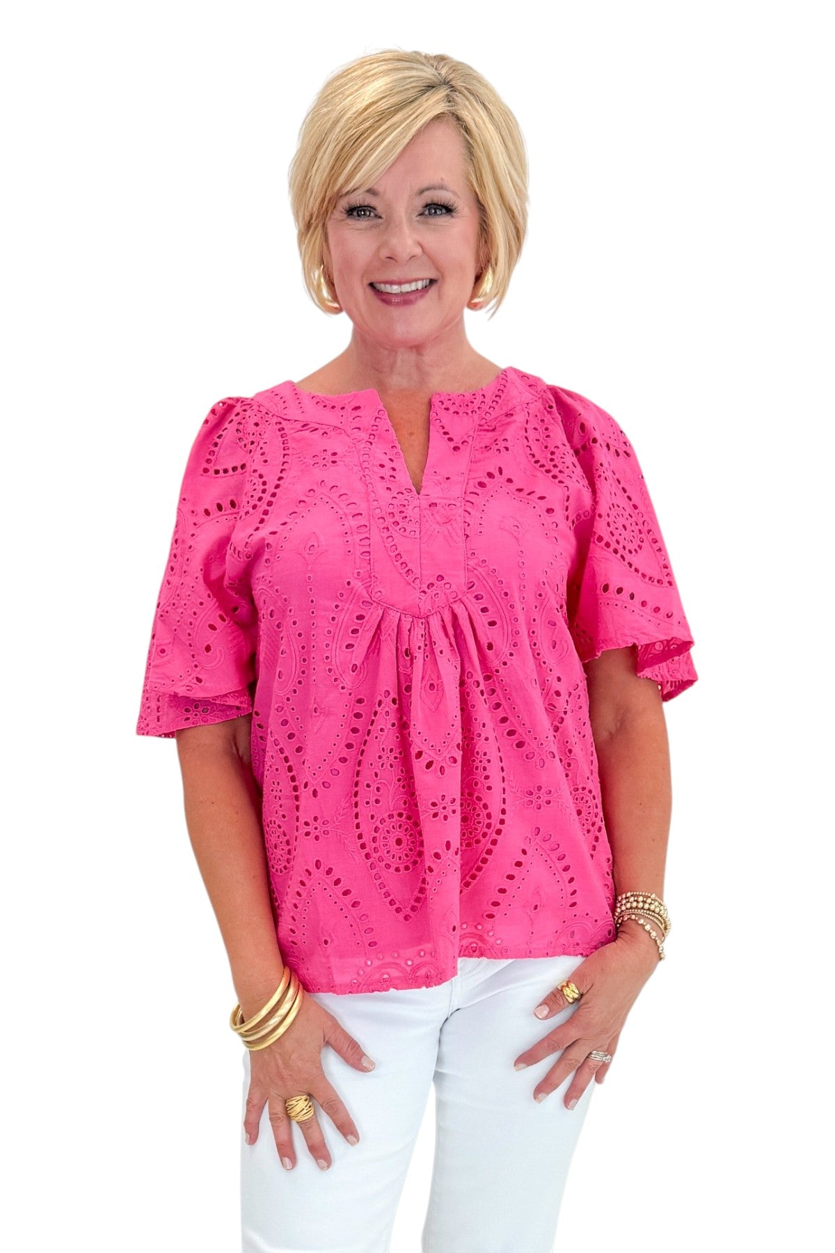 Front view of woman wearing Swagger Boutique’s Hot Pink Flutter Sleeve Eyelet Top with jeans against white studio background.