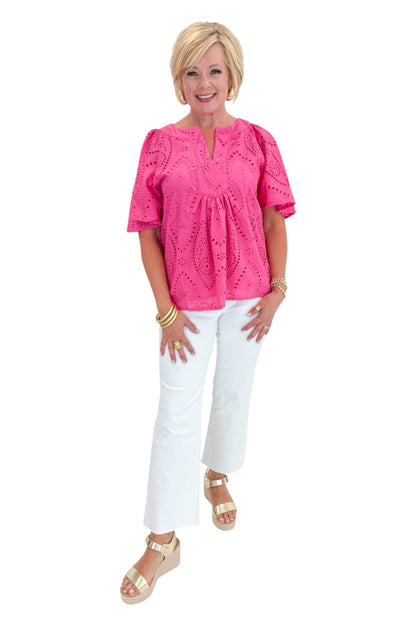 Front view of woman wearing Swagger Boutique’s Hot Pink Flutter Sleeve Eyelet Top with jeans against white studio background.