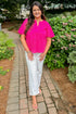 Front view of woman wearing Swagger Boutique’s Hot Pink Flutter Sleeve Eyelet Top with jeans walking down a path outside.