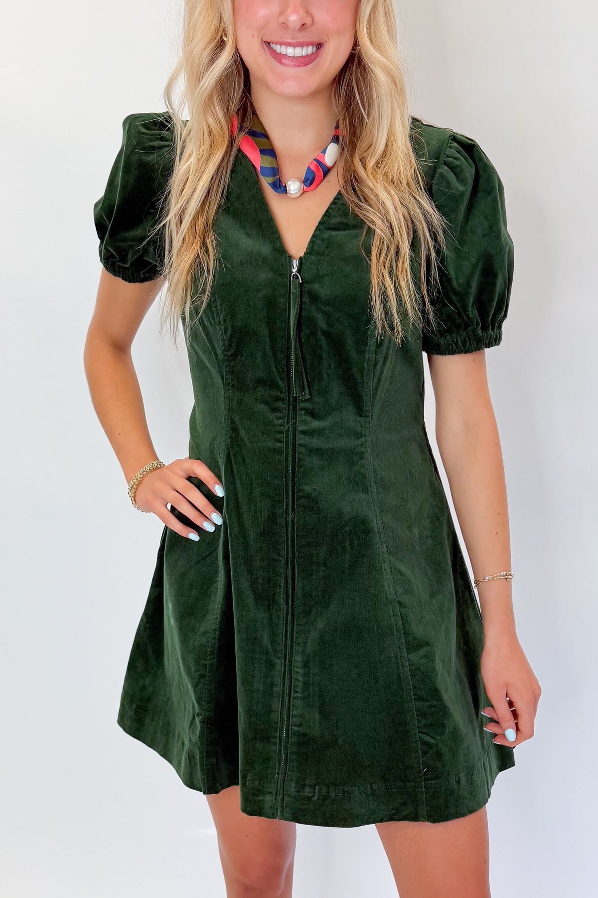 Front detail view of woman wearing Swagger Boutique’s Hunter Green Corduroy Mini Dress by Entro with boots against white studio background.