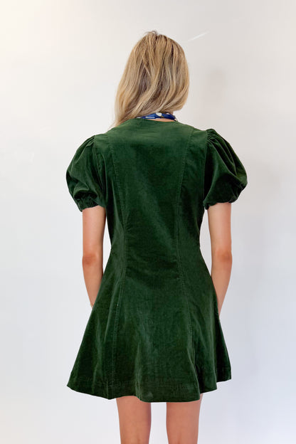 Back view of woman wearing Swagger Boutique’s Hunter Green Corduroy Mini Dress by Entro with boots against white studio background.