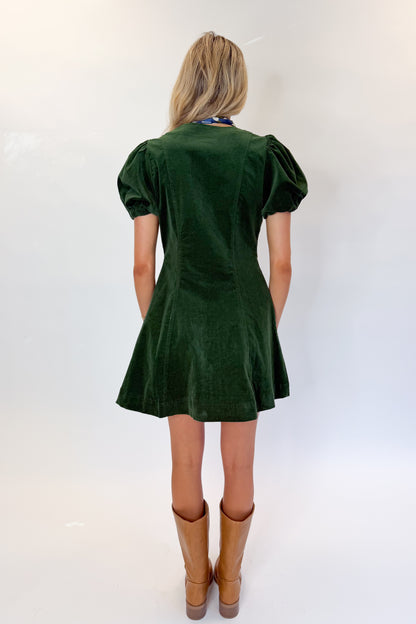 Back view of woman wearing Swagger Boutique’s Hunter Green Corduroy Mini Dress by Entro with boots against white studio background.