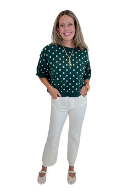 Front view of woman wearing Swagger Boutique’s Hunter Green Polka Dot Short Sleeve Sweater by Entro with jeans against white studio background.