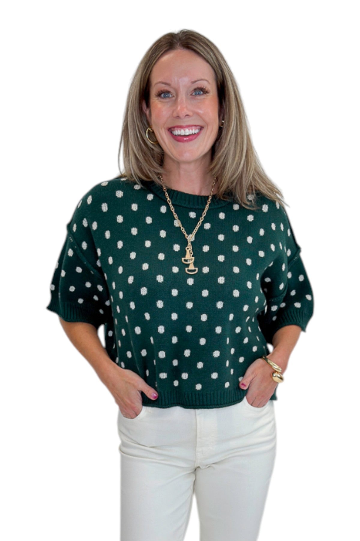 Front view of woman wearing Swagger Boutique’s Hunter Green Polka Dot Short Sleeve Sweater by Entro with jeans against white studio background.