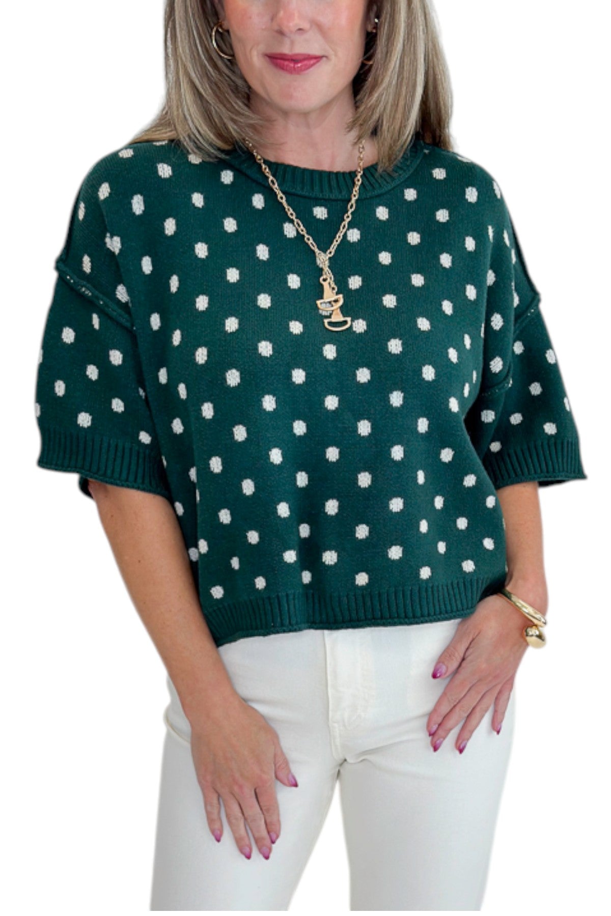 Front detail view of woman wearing Swagger Boutique’s Hunter Green Polka Dot Short Sleeve Sweater by Entro with jeans against white studio background.