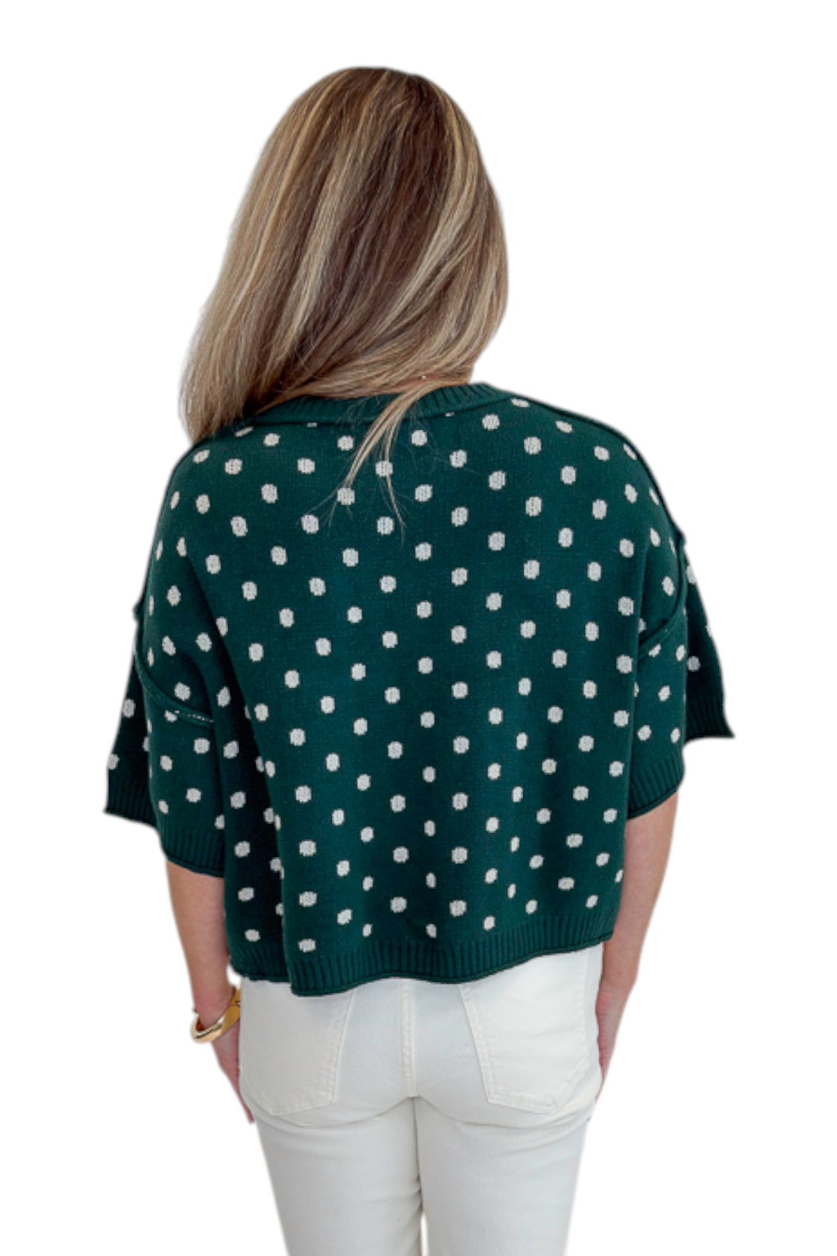 Back view of woman wearing Swagger Boutique’s Hunter Green Polka Dot Short Sleeve Sweater by Entro with jeans against white studio background.