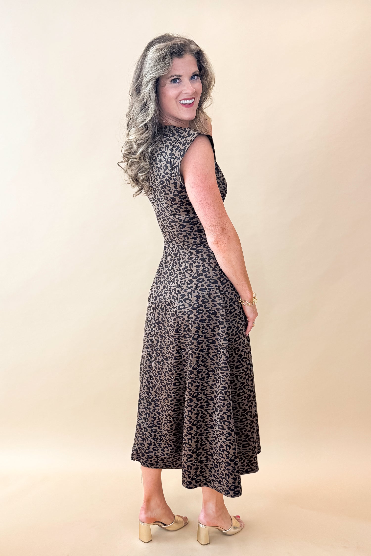 Side view of woman wearing Leopard Suede Midi Dress against tan studio background.