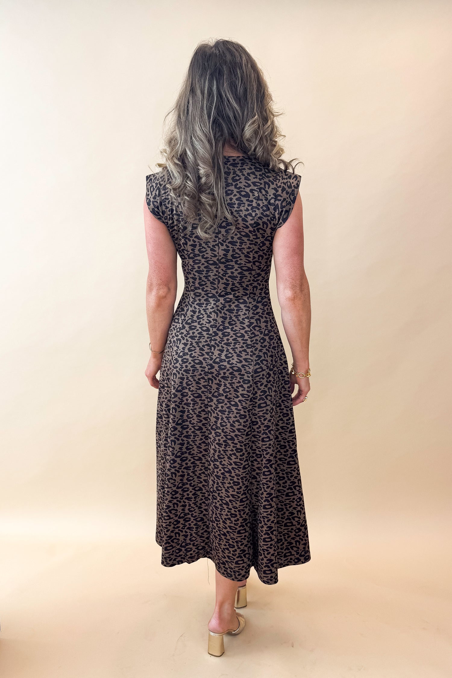 Back view of woman wearing Leopard Suede Midi Dress against tan studio background.