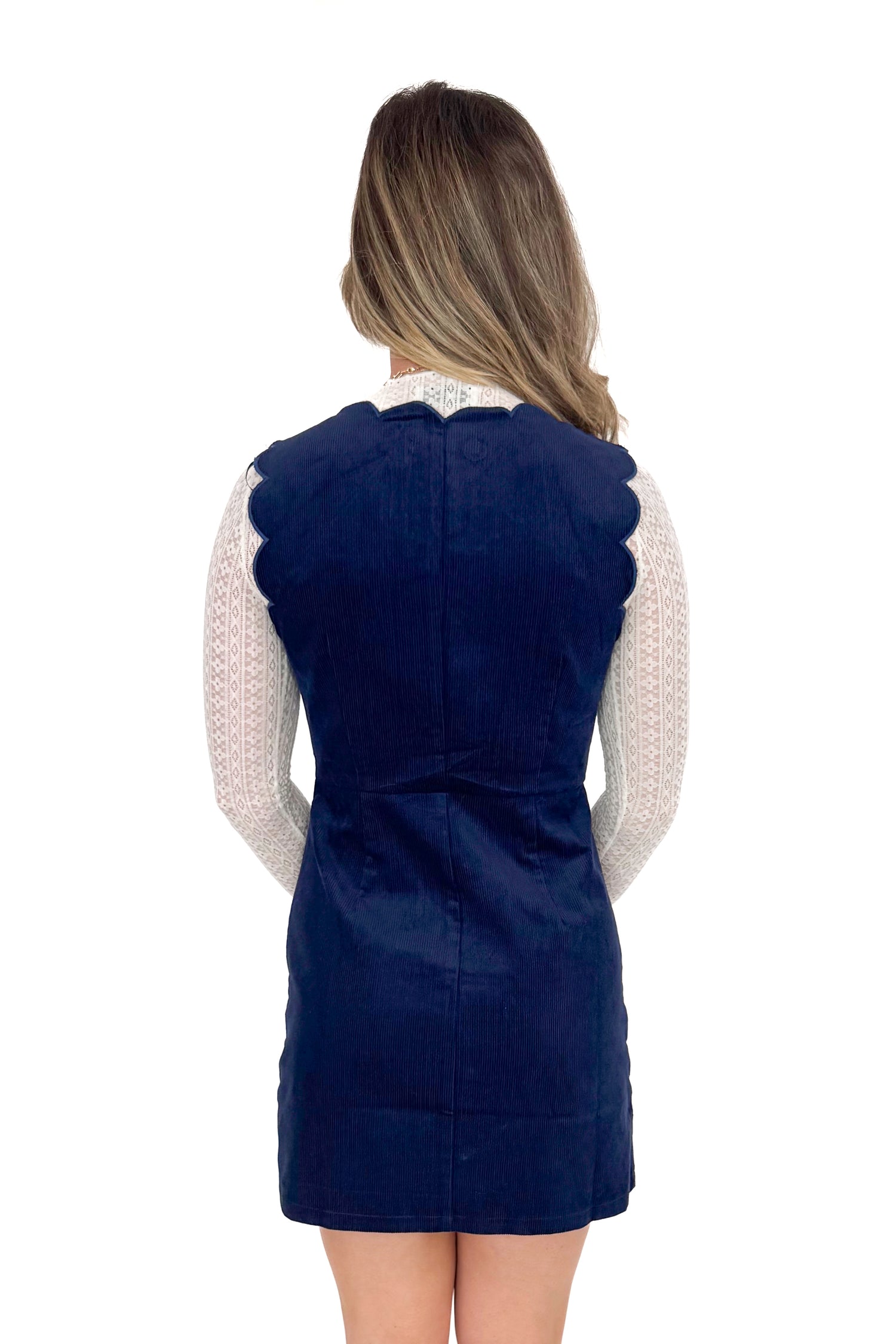 Back view of model wearing Navy Corduroy Scallop Lined Dress with boots against white studio background.