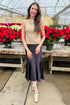 Front view of woman wearing Gold Sleeveless Sweater with skirt by holiday decor.