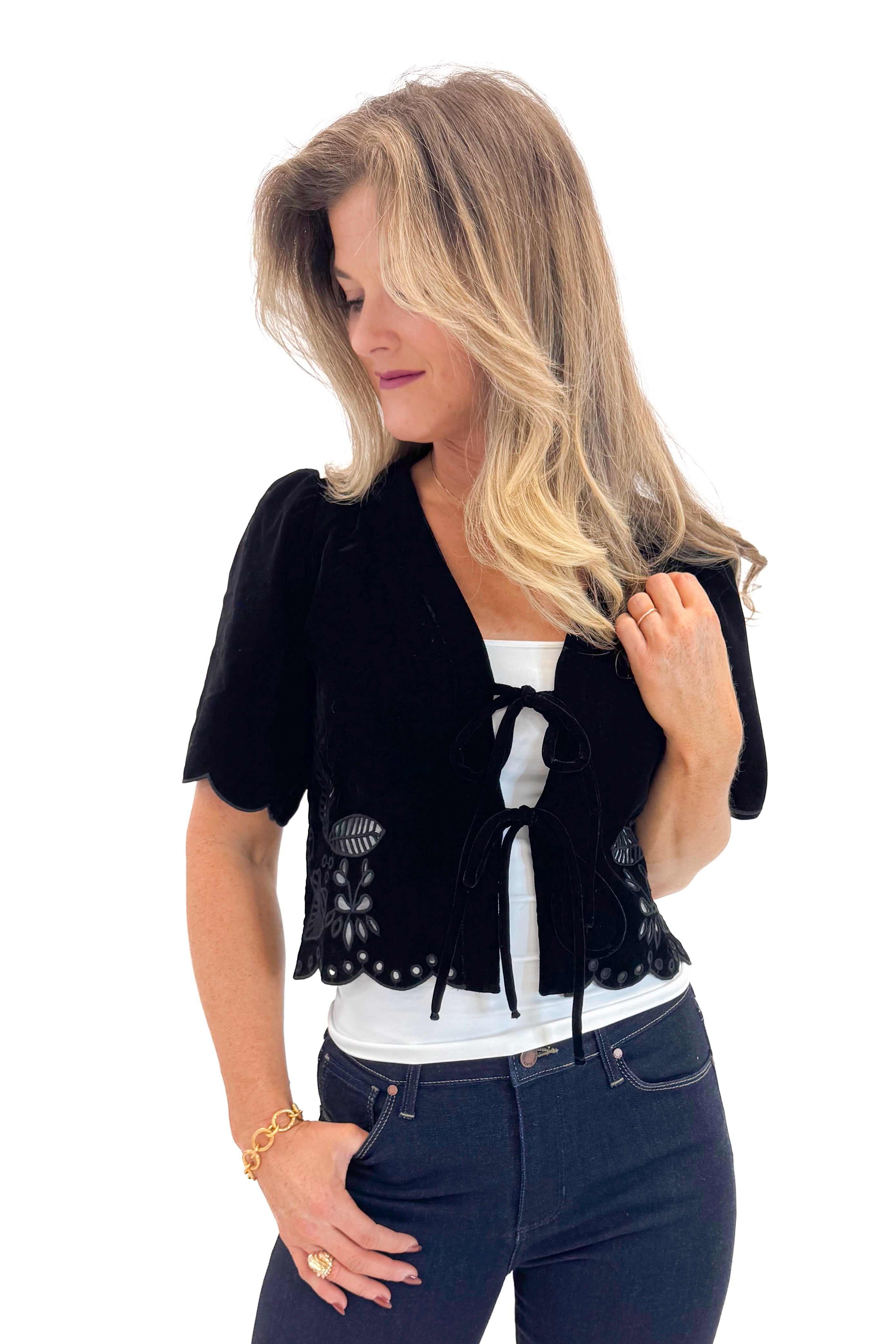 Front view of woman wearing Black Velvet Tie Front Top with jeans against white studio background.