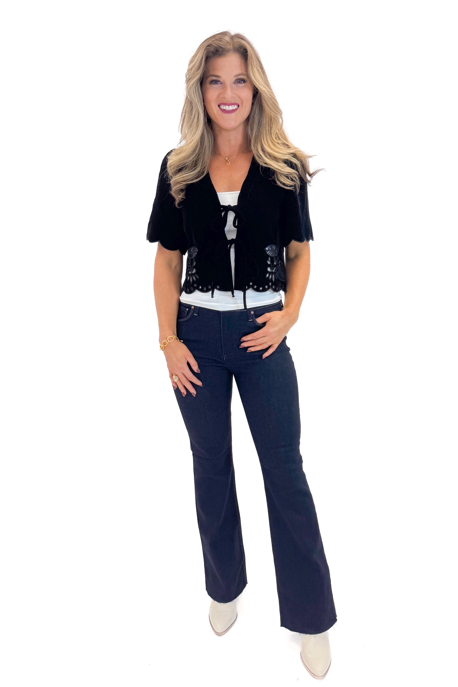 Front view of woman wearing Black Velvet Tie Front Top with jeans against white studio background.
